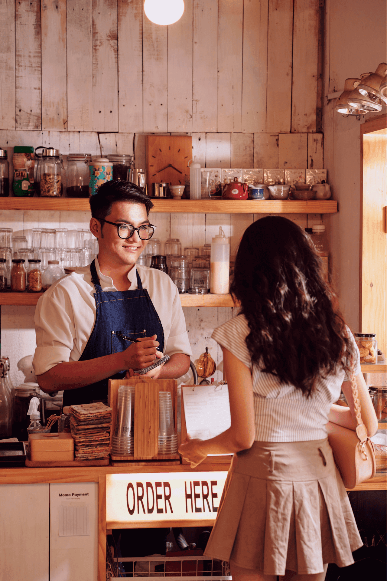 Imagen decorativa de una persona detrás del mostrador tomando la orden a otra persona